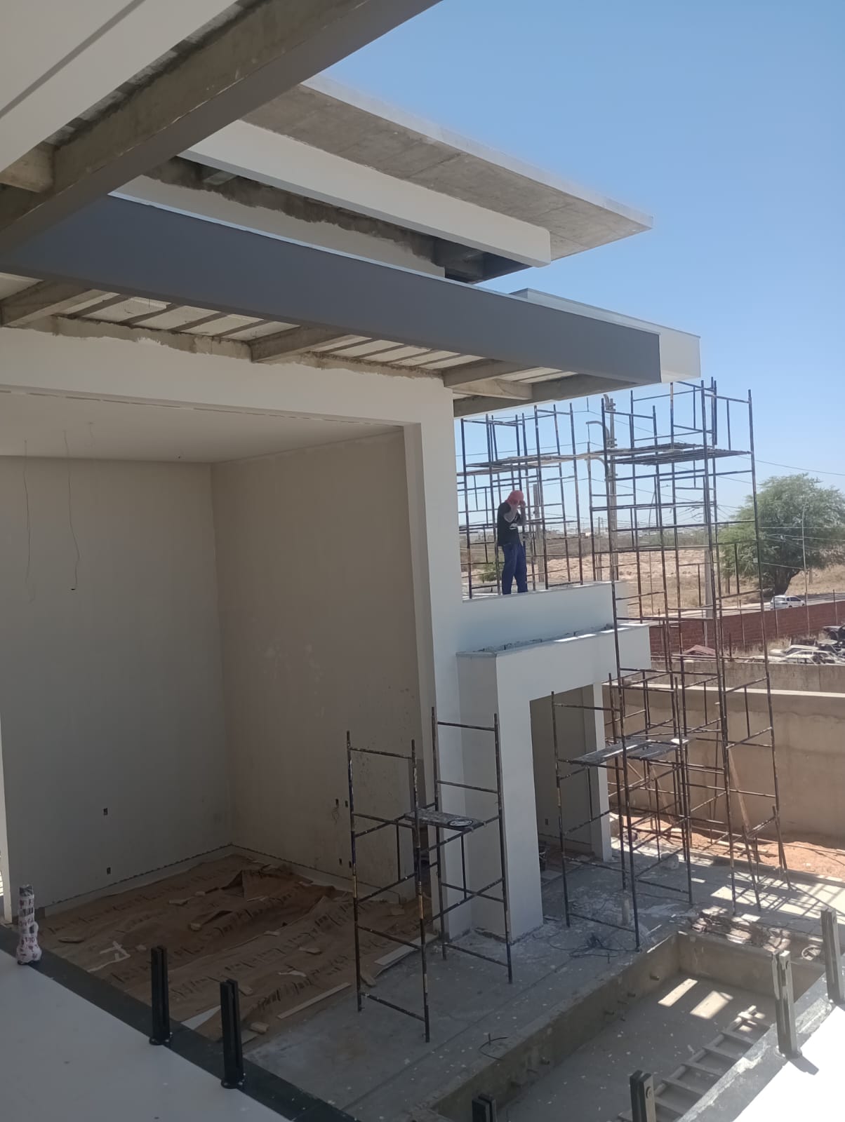 Pintor em andaime com paredes e vigas pintadas de branco